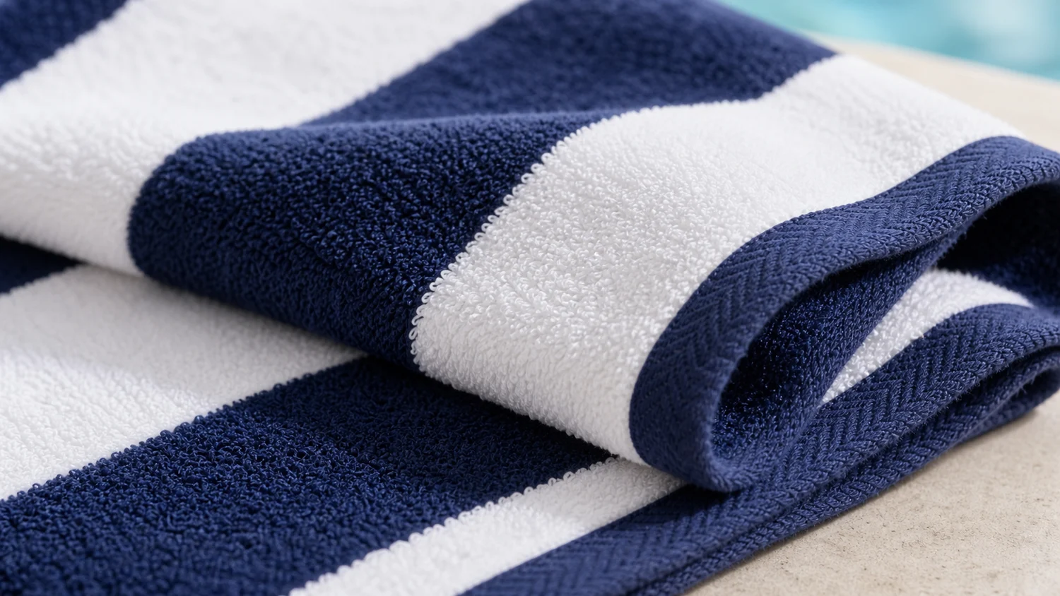 Macro close-up of navy and white cabana stripe hotel pool towel terry loops and stitched edge