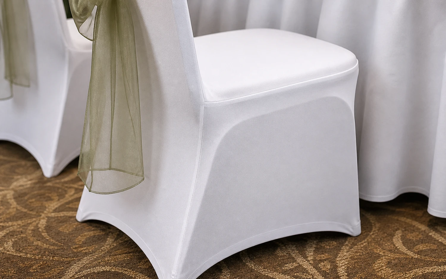 Close-up of covered banquet chairs with tied fabric accents