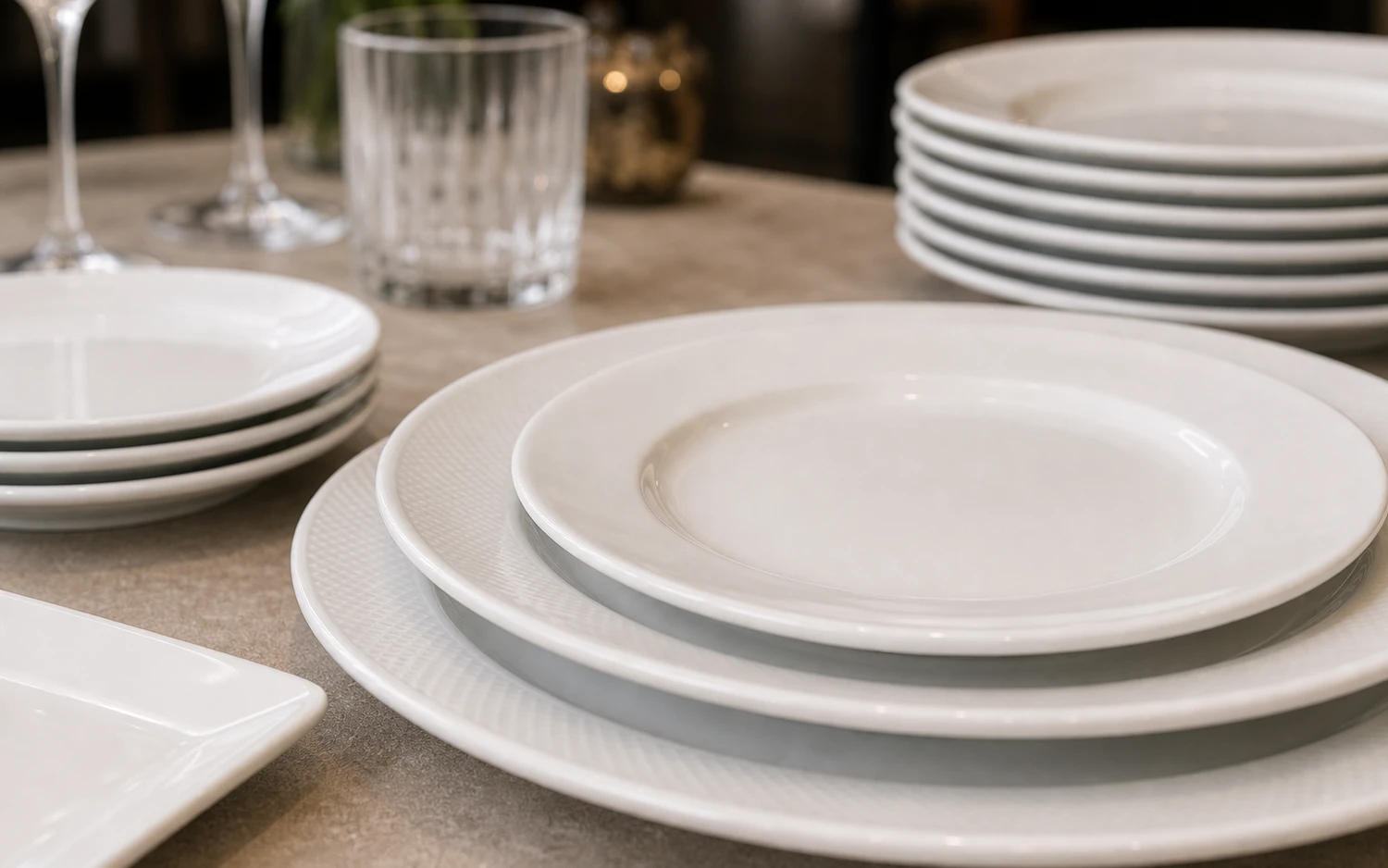 Close-up of white textured porcelain dinner plates with cup and glassware