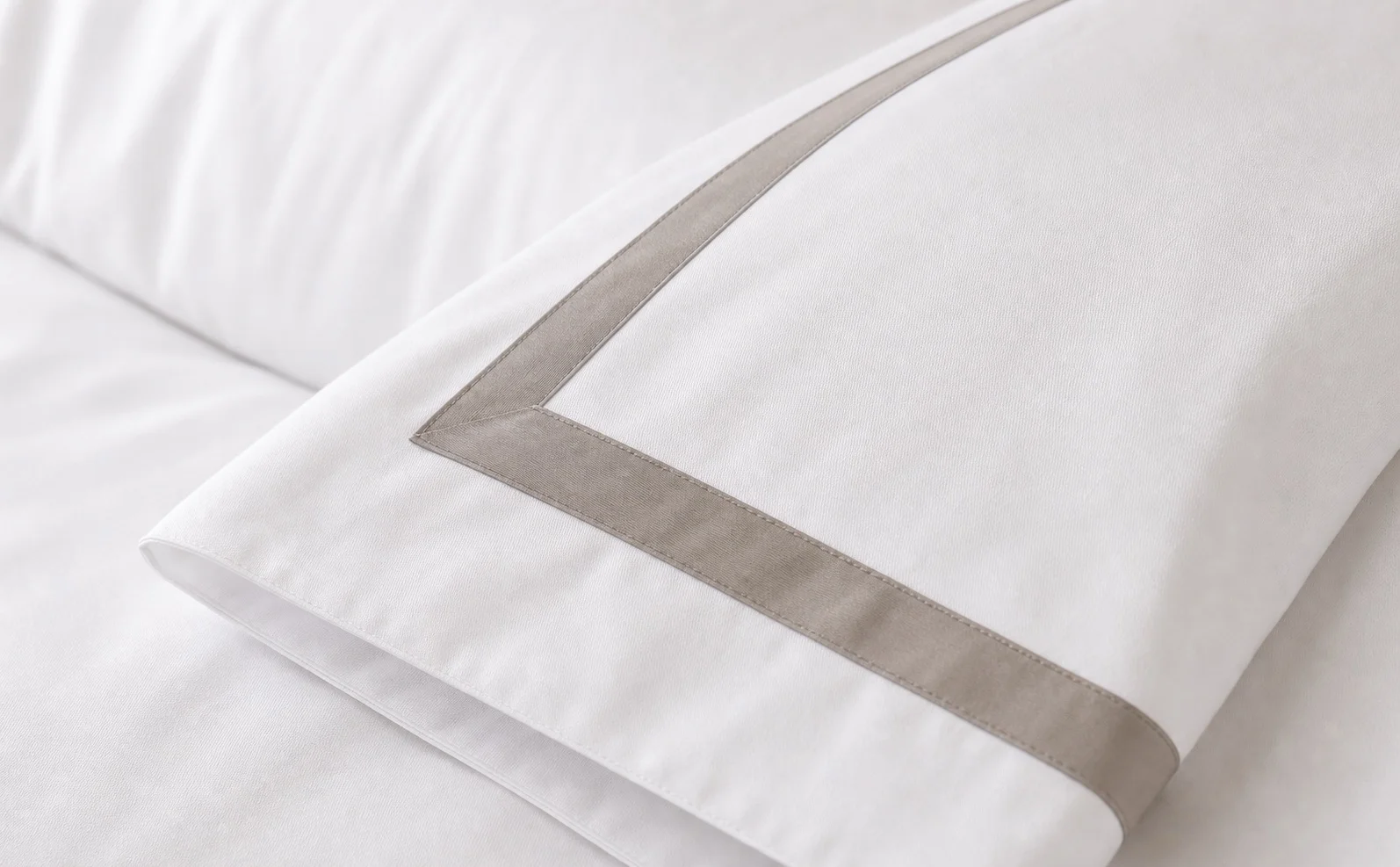 Close-up of hotel duvet cover with wide taupe contrast border and corner seam