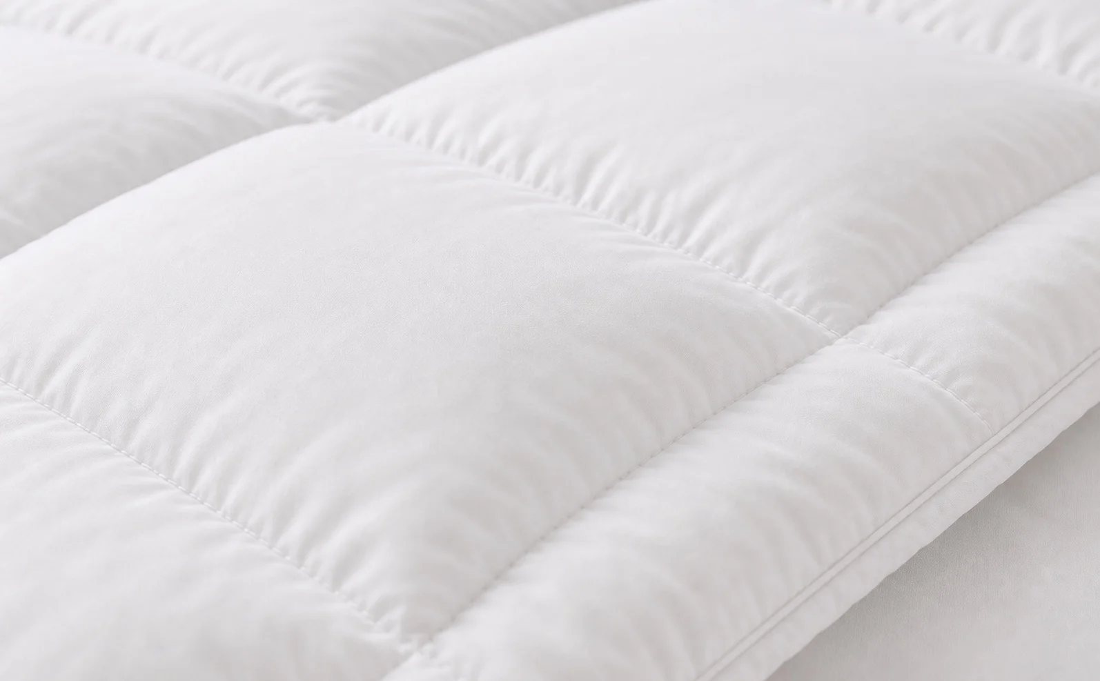 Close-up of white hotel microfiber quilt with stitched channel construction