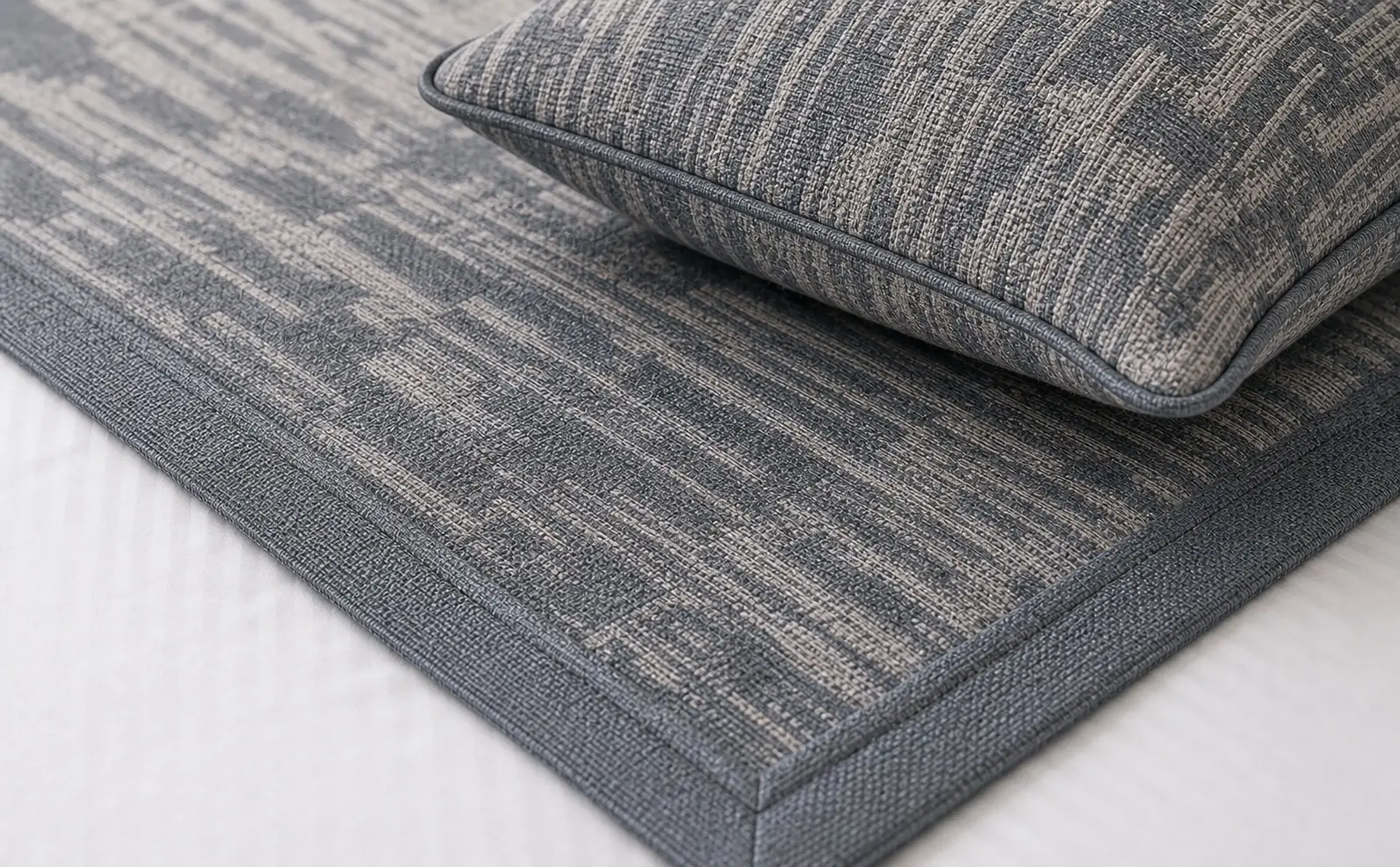 Close-up of slate blue jacquard bed runner fabric with piped cushion edge