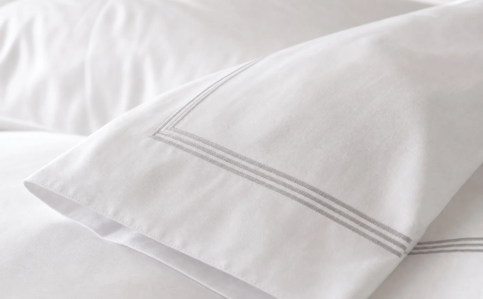 Close-up of white hotel linen with embroidered frame border stitching